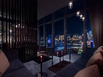 A luxury hotel suite with a city view, featuring modern furniture and large windows.