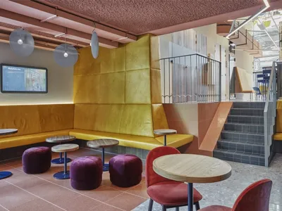 A modern cafe interior with yellow leather seating and round tables.