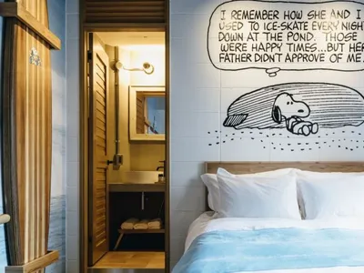 A modern minimalist bedroom with a white wall featuring a Snoopy comic strip