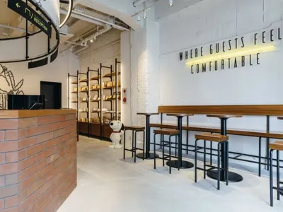 A modern restaurant cafe interior with brick and concrete finishes, featuring seating areas, a bar, and decorative elements.