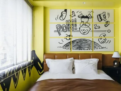 A modern bedroom with yellow walls and brown leather headboard