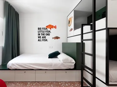 A minimalist bedroom featuring a white bed with green accents, green curtains, and a wall quote about fish.