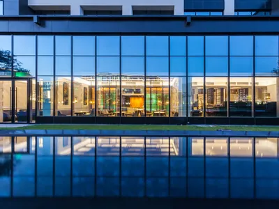 A modern hotel lobby featuring large glass windows reflecting the interior and a glossy floor.