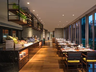 A modern restaurant features a buffet with a selection of fruits and vegetables, served on wooden tables with marble countert