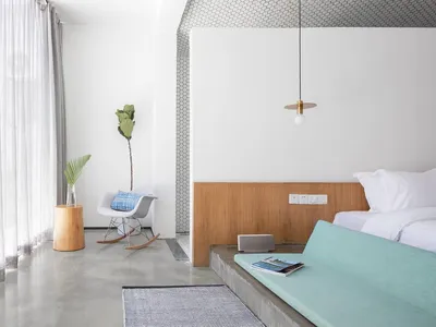 Modern minimalist bedroom featuring a concrete floor, white walls, and wood accents.