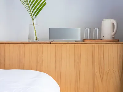 A minimalist bedroom with wooden furniture and a white bedspread.
