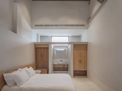 Bedroom with a white bed, wooden ceiling, and minimalist decor.
