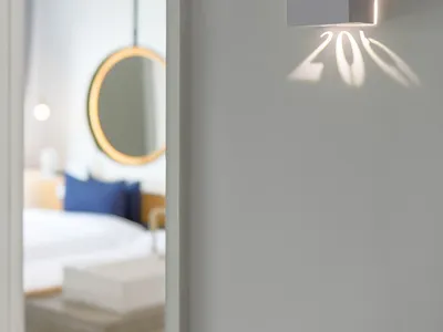 A minimalist hotel room with a grey cube-shaped light fixture displaying the room number 206.