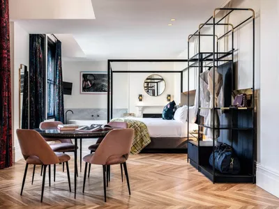 A modern hotel room suite featuring a wood floor, marble bathtub, and cloth.