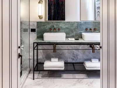 Modern bathroom with marble tiles, white sinks, and black metal accents.