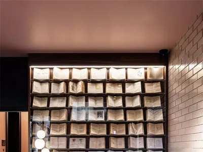 現代居家辦公室，設有書桌與椅子，特色為開放式書架牆展示帶燈光的書籍，以及綠色大理石