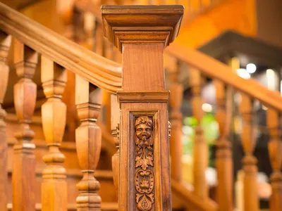 A detailed wooden staircase with intricate carvings and a decorative column.