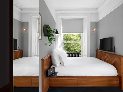 A minimalist bedroom with a wooden headboard, white bedding, and a wooden floor.