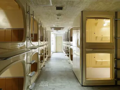 A modern capsule hotel with multiple pods, each featuring a bed and personal space.
