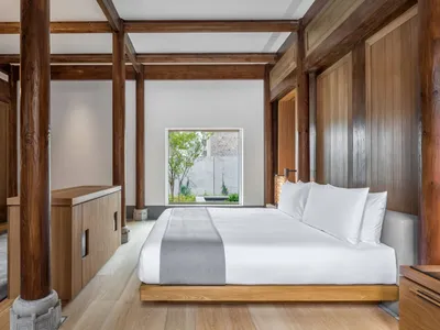 A modern minimalist bedroom featuring wooden beams and a large window