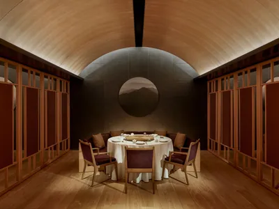 Modern restaurant interior with round table, upholstered chairs, and elegant decor.