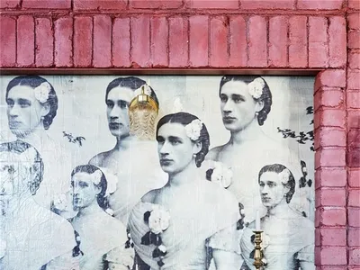 A restaurant interior with a pink brick wall featuring a poster of men in suits with flowers in their hair.