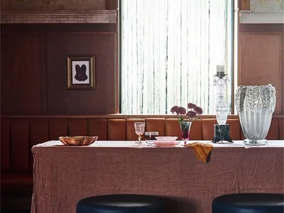 An industrial-themed restaurant interior with leather seating and fabric-covered tables.