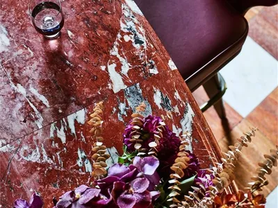 Industrial restaurant interior with dark-red marble countertop and purple flowers.