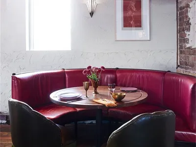 Circular seating area with red leather booths and wooden table in an industrial-style restaurant interior