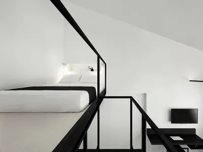 A minimalist bedroom with a black and white color scheme, featuring a loft bed, desk, and sleek design elements.