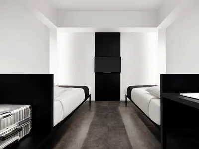 Modern hotel room with two single beds, white bedding, metallic black headboards, and a television mounted on the wall in a m
