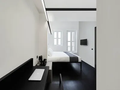 Modern minimalist bedroom featuring a metal-framed bed, wooden flooring, and fabric bedding.