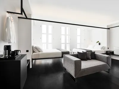 A modern bedroom interior with neutral-colored furnishings, featuring two beds and a minimalist design.