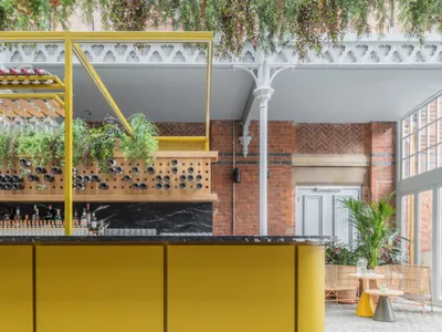 A modern restaurant bar with yellow walls, wooden elements, and stone accents.