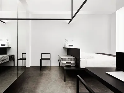 Modern minimalist bedroom featuring black and white decor with metallic luggage and furniture.