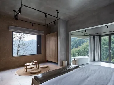 極簡臥室擁有混凝土牆面，透過大型窗戶可眺望山景。