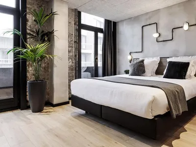 Modern industrial hotel room with concrete walls, wooden furniture, and metal accents.
