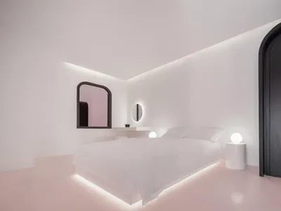 A minimalist bedroom with a white bed on concrete flooring, black wardrobe, and round glass light fixtures.