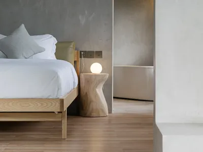 A minimalist bedroom with a wooden bed and light fixture.