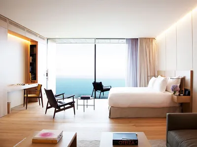 極簡風格的酒店臥室，配有大床、簡約家具，透過大窗與陽台可欣賞海景。