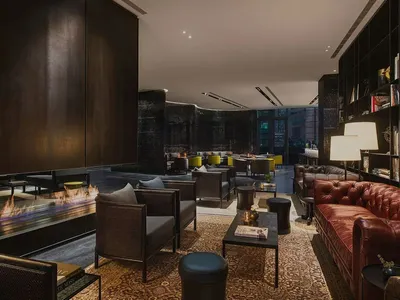 Interior design of a modern industrial hotel lobby featuring concrete and leather furniture.
