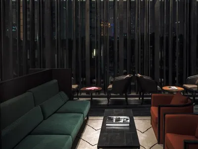Interior design of a modern hotel lounge featuring black accent furniture, green velvet seating, and metal tables.