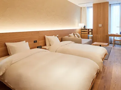 Modern, minimalist hotel room with wood paneling and light-colored bedding.