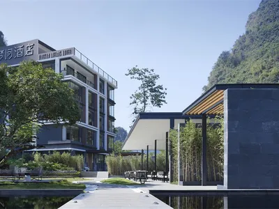現代酒店混凝土玻璃外觀，周圍環繞茂密綠意。