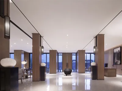 Modern hotel lobby with sleek, wooden columns, minimalist decor, and floor-to-ceiling glass windows.