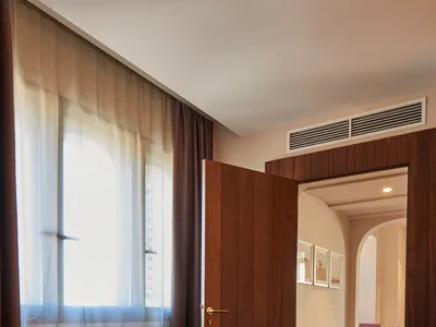A modern hotel suite featuring wooden furnishings and a large window.