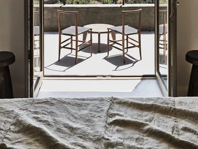 A minimalist bedroom featuring wooden furniture and a view of the sea.