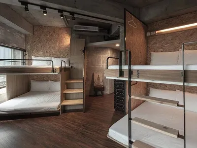 A modern minimalist bedroom with wooden bunk beds, white bedding, and a rustic ladder.