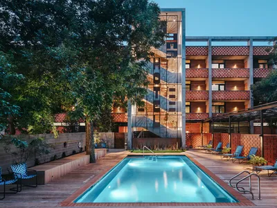 Hotel pool deck featuring brick, concrete, and wood materials