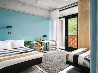 Modern bedroom featuring concrete walls, wooden furniture, and striped bedding.