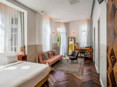 Modern hotel room with wooden furniture, large windows, and a comfortable seating area.