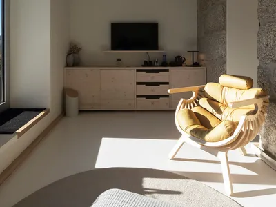 Modern minimalist living room with concrete walls, wooden furniture, and a yellow upholstered chair.