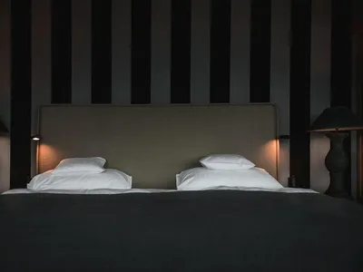 現代簡約臥室，配有雙人床、白枕頭，以及灰黑條紋牆面。