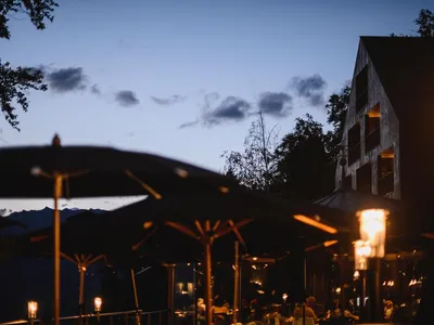 Nighttime scene of a modern restaurant with metallic decorations and illuminated patio lanterns.