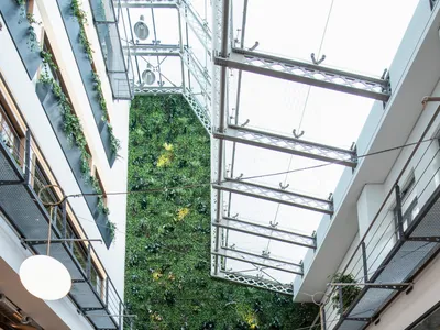A modern cafe restaurant with concrete floors, walls, and ceiling, featuring a vertical garden wall, wooden furniture, and po